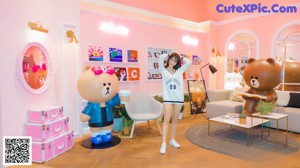 A woman sitting on the floor in front of a pink wall.