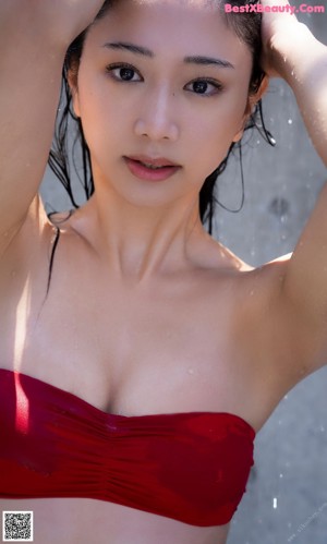 A woman in a red bikini sitting by a swimming pool.