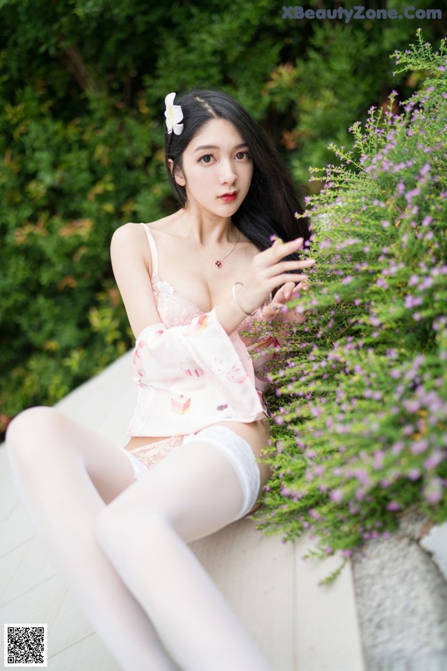A woman sitting on a bench in a pink lingerie.