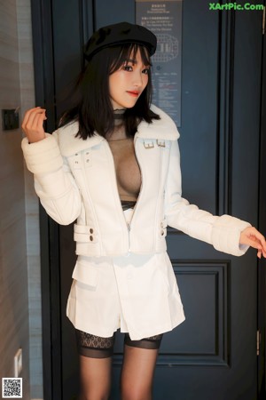 A woman in a black top and white skirt posing for the camera.