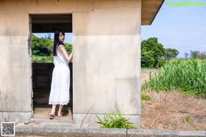 A woman in a white dress is tying up her bare feet.