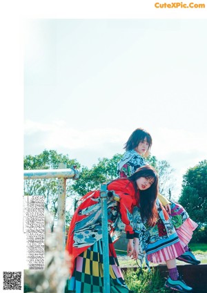 A woman in a colorful kimono standing on a sidewalk.