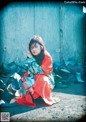 A woman in a colorful kimono standing on a sidewalk.