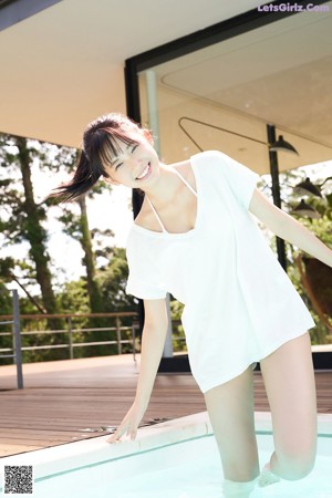 A woman in a white bikini laying on the edge of a pool.