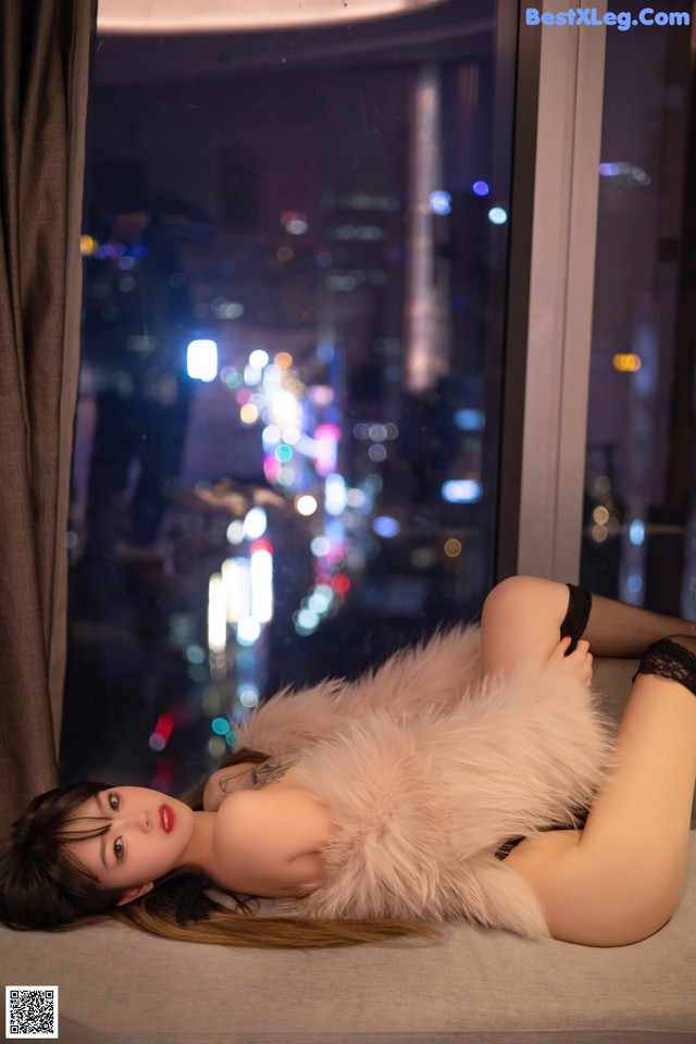 A woman laying on a bed in front of a window.