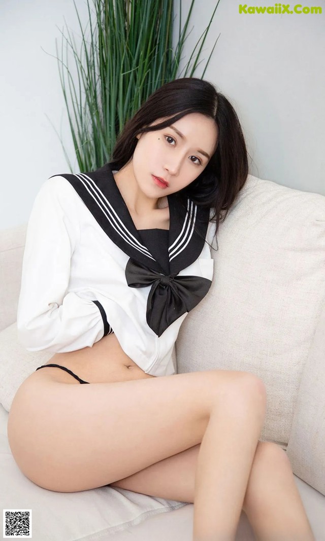 A woman in a sailor outfit sitting on a couch.