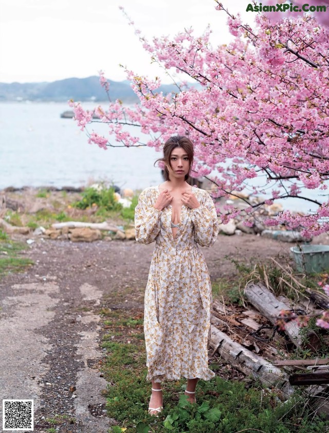 A woman standing in front of a flowering tree.