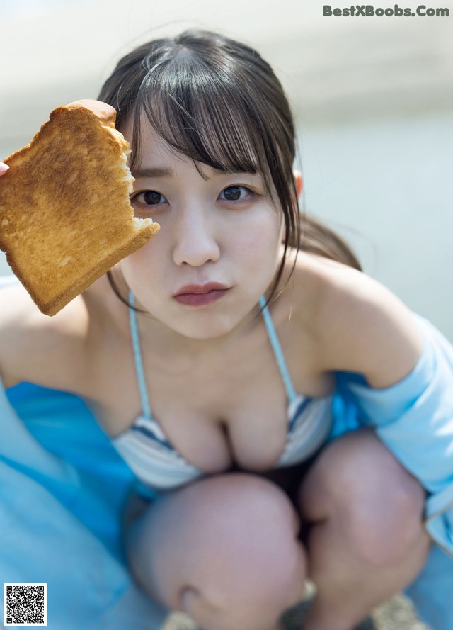 A woman in a bikini holding a piece of bread.