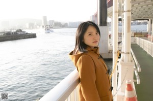 A woman in a white shirt standing next to a boat.