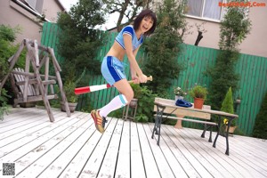 A woman in a blue and white uniform holding a baseball bat.