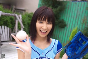 A woman sitting on a bench holding a baseball bat.