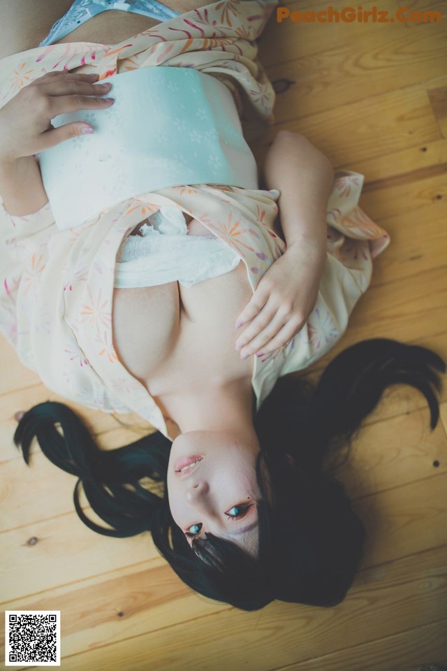 A woman laying on the floor in a kimono.