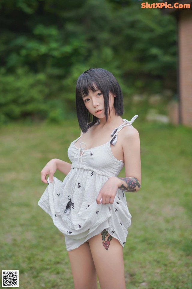 A woman in a white dress standing in the grass.