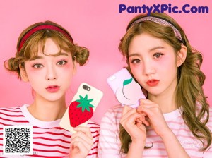 Two young women standing next to each other on a pink background.