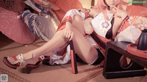 A woman with pink hair sitting on a bed.