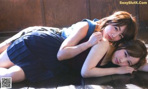 A couple of women sitting on top of a blue couch.