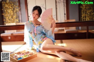 A woman in a blue kimono sitting on a tatami mat.