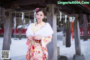 A woman in a kimono standing in front of a lantern.