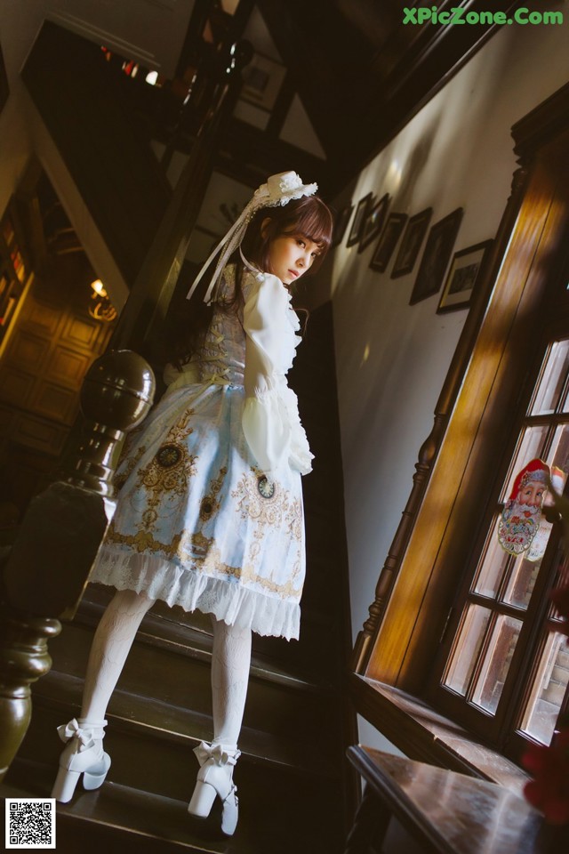A woman in a white dress is standing on the stairs.