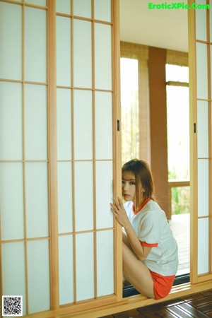 A woman sitting on a wooden deck with her legs crossed.