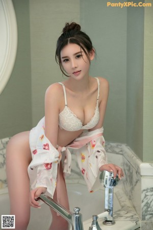 A woman in a white lingerie posing in a bathroom.