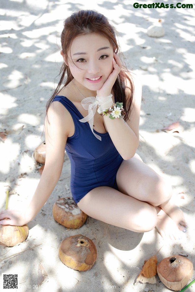 A woman in a blue bathing suit sitting on the beach.