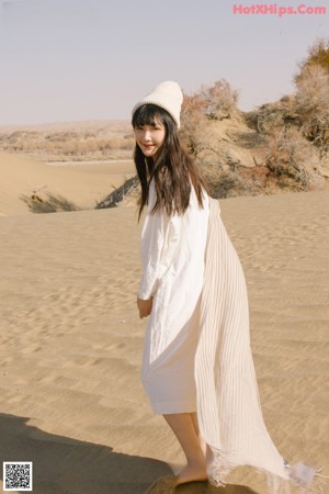 A woman sitting on top of a sandy beach.