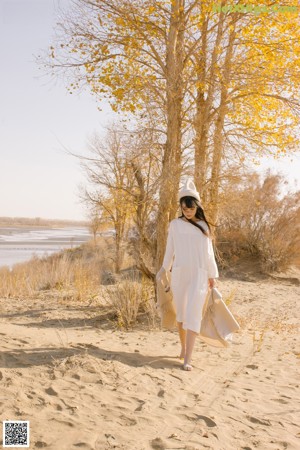 A woman in a white dress laying on a sand dune.