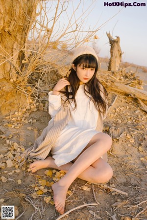 A woman in a white dress and hat standing on a sand dune.