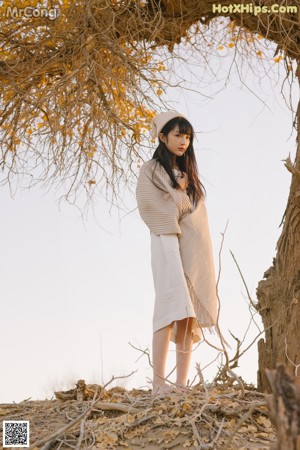 A woman standing on top of a sand dune.