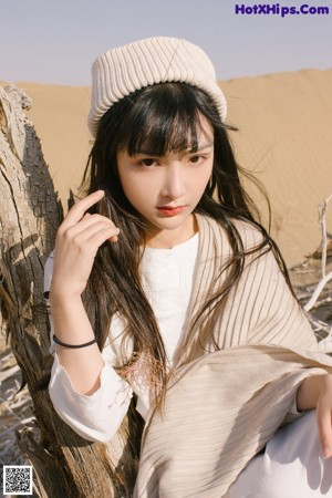 A woman sitting on top of a sand dune in the desert.