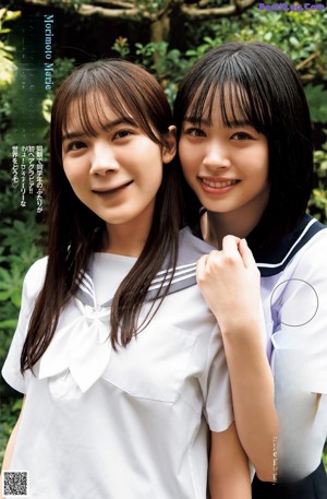 Two young women in school uniforms holding hands on a street.