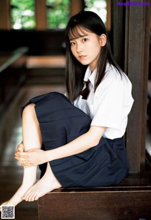 A young woman in a school uniform posing for a picture.