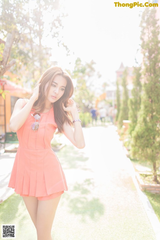 A woman in a pink dress is posing for a picture.