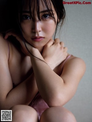 A naked asian woman laying on a bed.