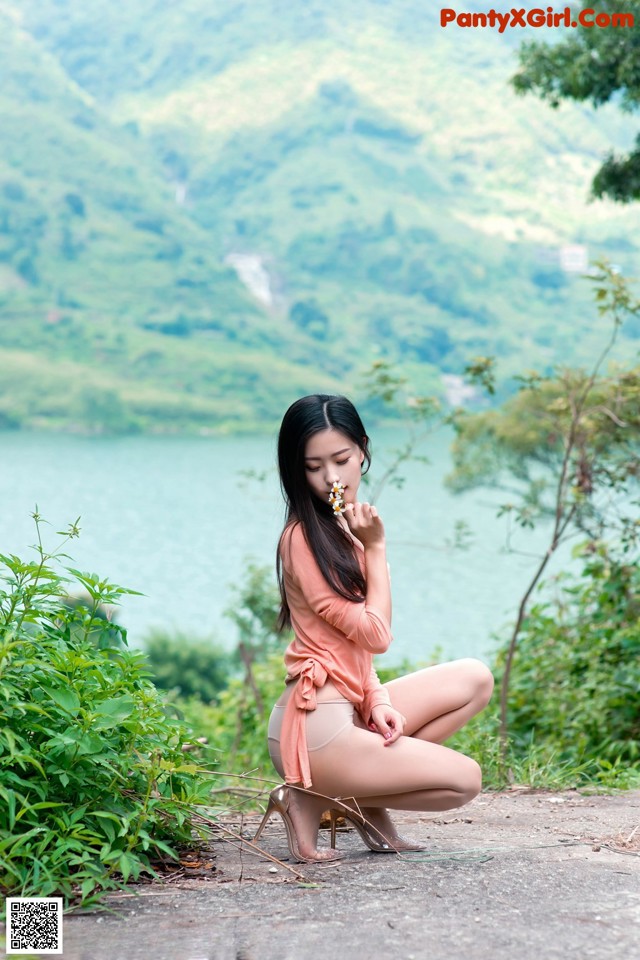 A woman sitting on the ground next to a body of water.