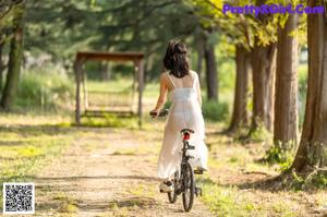 A woman in a white dress standing on a dirt road.