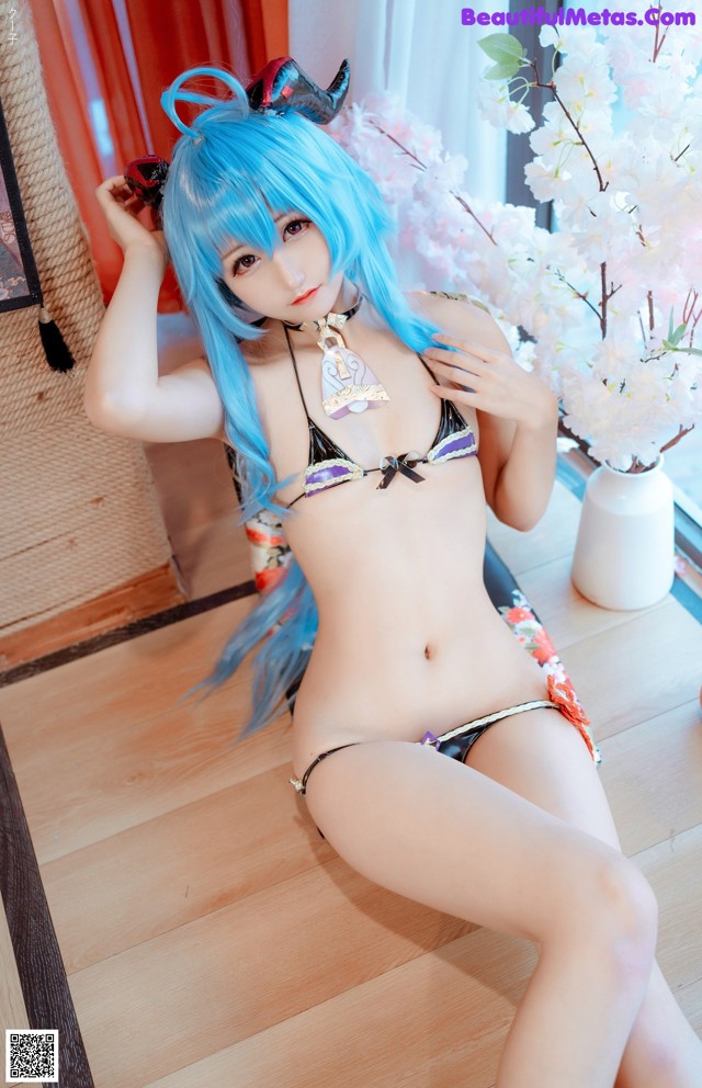 A woman in a bikini sitting on a wooden floor.