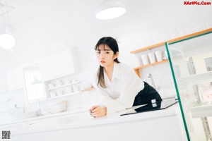 A woman sitting on the floor in a kitchen.