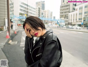 A woman in a blue and black sweater leaning against a fence.