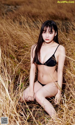 A woman in a white bikini standing on a rock.