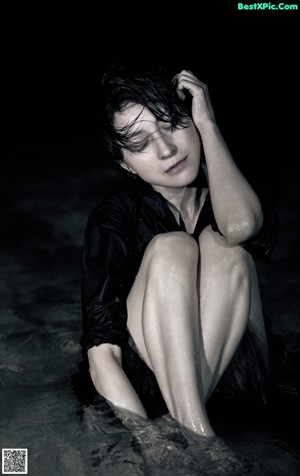 A woman in a white tank top is covered in water droplets.