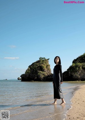 A woman standing in the middle of a dirt road.