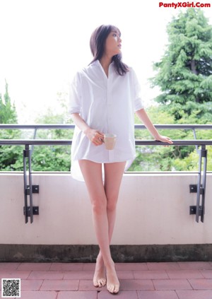 A woman in a green tank top and white shorts posing for a picture.