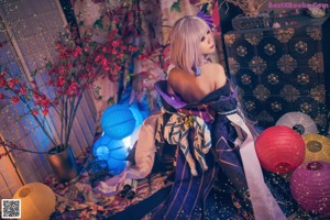 A woman in a blue and purple kimono sitting on a bed.