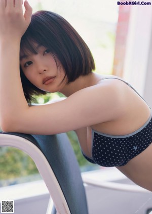 A woman sitting on a red chair in front of a ping pong table.