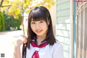 A woman in a school uniform standing in front of a house.