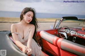 A woman sitting in the back of a red car.