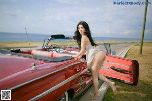 A woman sitting in the driver's seat of a red car.