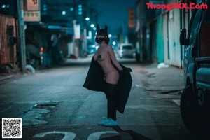 A woman wearing a mask and a jacket standing on a bridge.